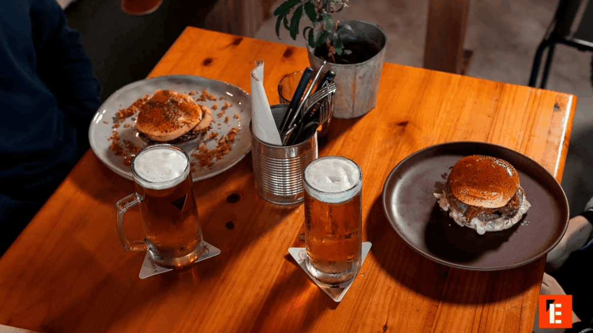 Cerveza y hamburguesas en una mesa de madera.