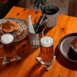 Cerveza y hamburguesas en una mesa de madera.
