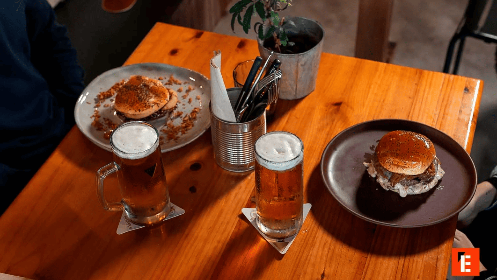 Cerveza y hamburguesas en una mesa de madera.