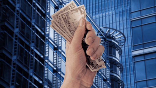 mano con billetes y edificios de oficinas