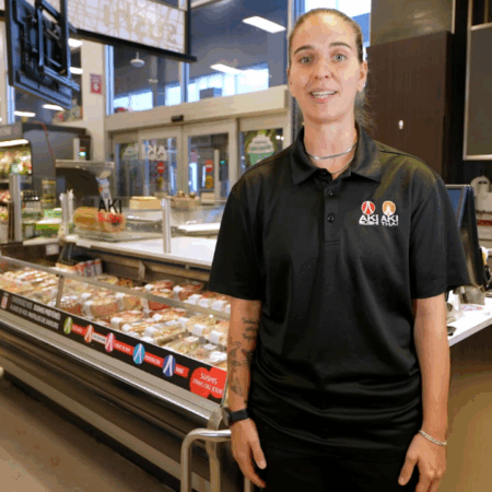 Employée devant un comptoir de sushis dans un magasin.