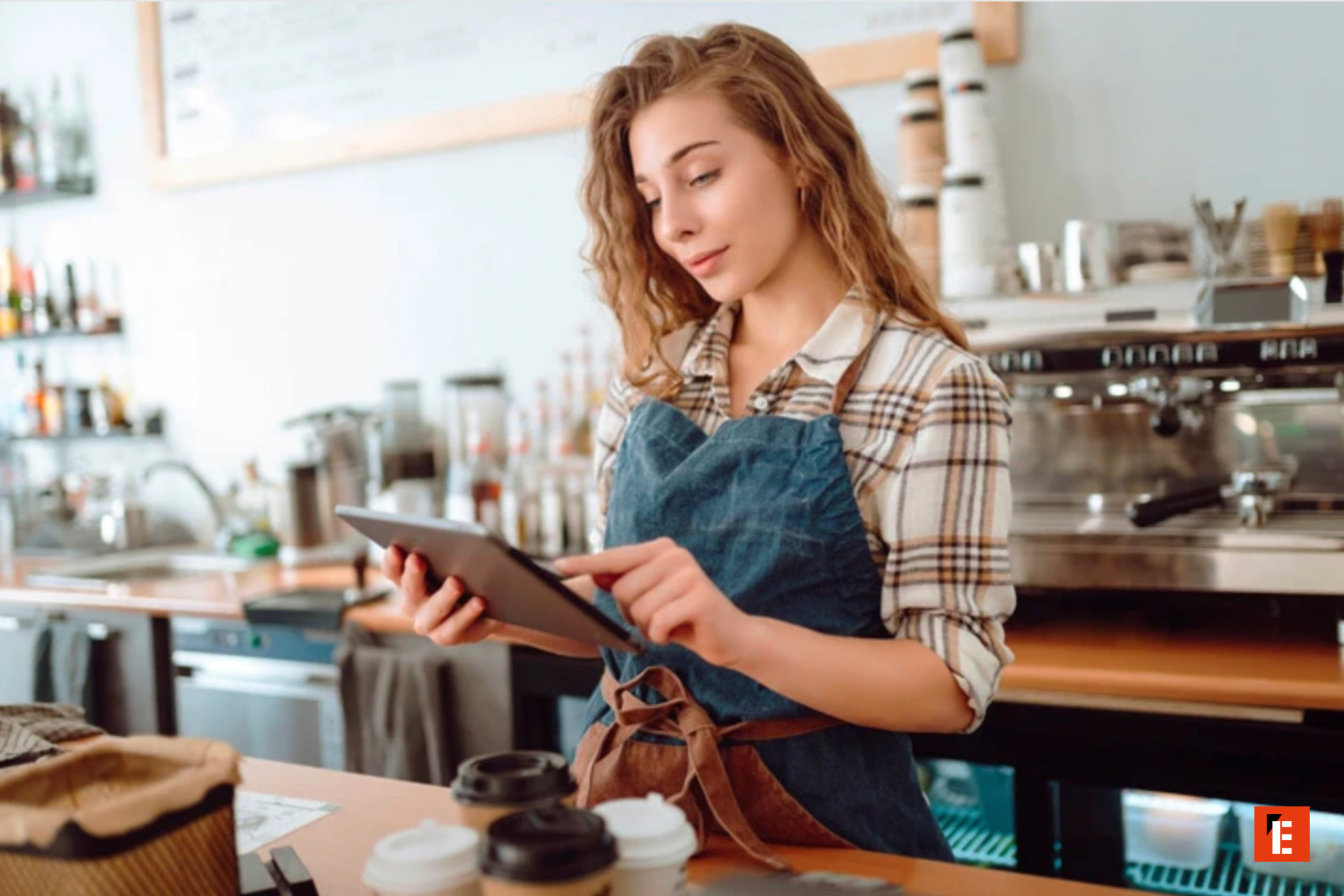 Jeune barista utilisant une tablette au café.