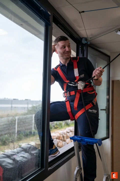 technicien en harnais sécurisé à la fenêtre