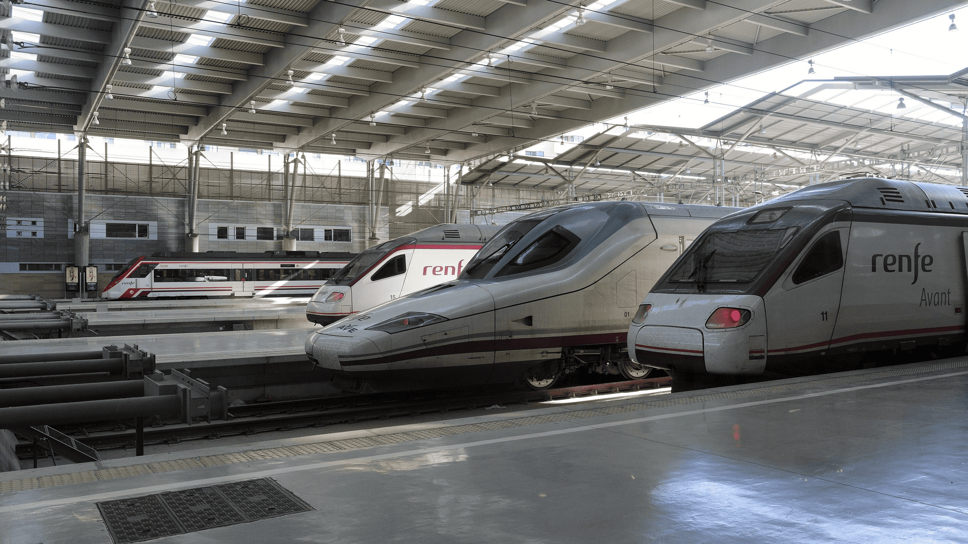 Varios trenes de Renfe en una estación moderna.