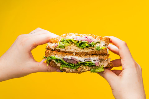 handheld whole grain chicken sandwich with lettuce