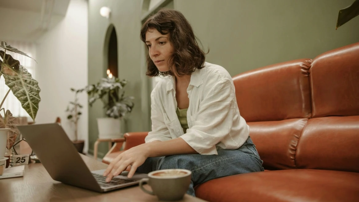 donna sul divano con il computer e un caffè