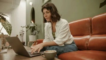 donna sul divano con il computer e un caffè