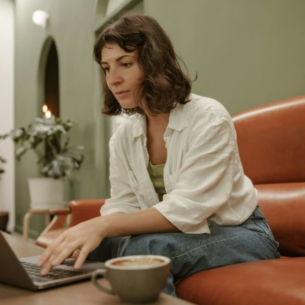 donna sul divano con il computer e un caffè