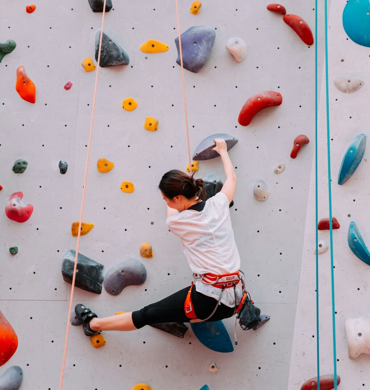 escalade intérieure : femme sur mur coloré