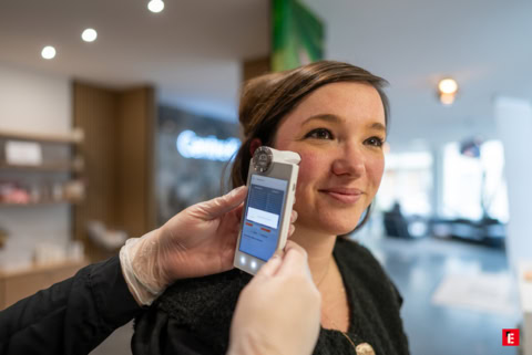 une cliente se faisant analyser la peau avec un appareil