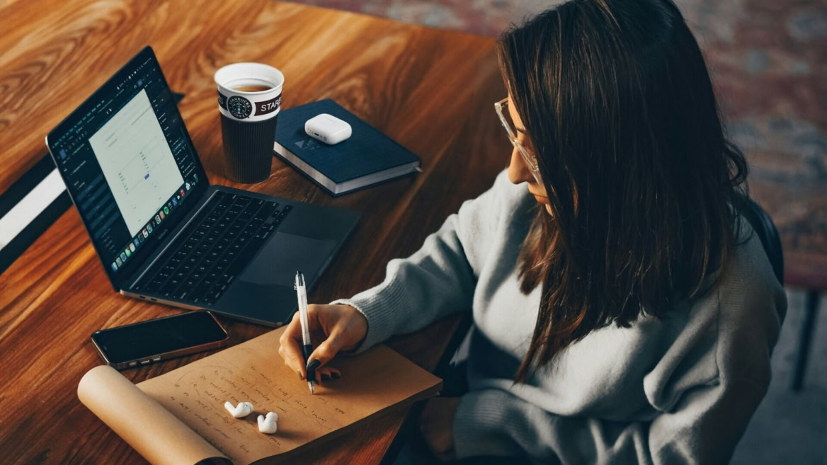 persona che annota qualcosa su un blocco note sulla scrivania