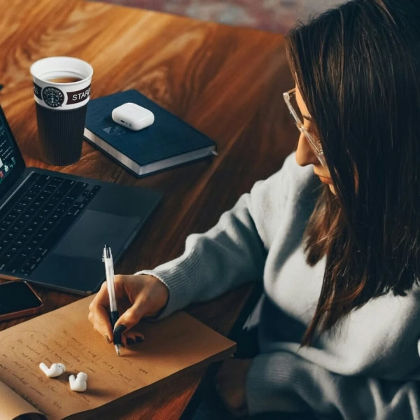 persona che annota qualcosa su un blocco note sulla scrivania