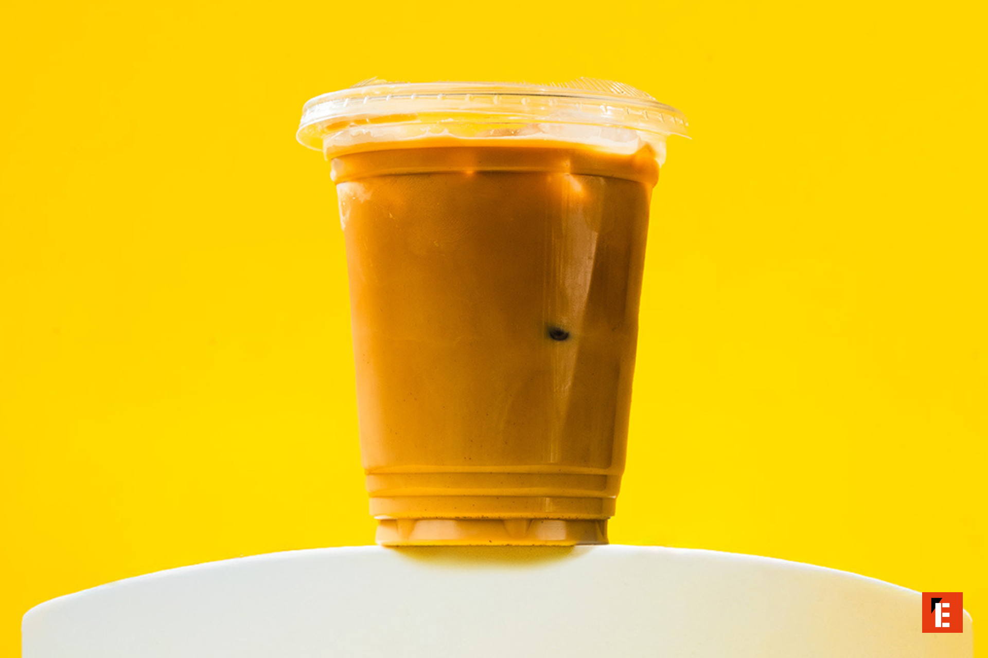 iced coffee in plastic cup on yellow background