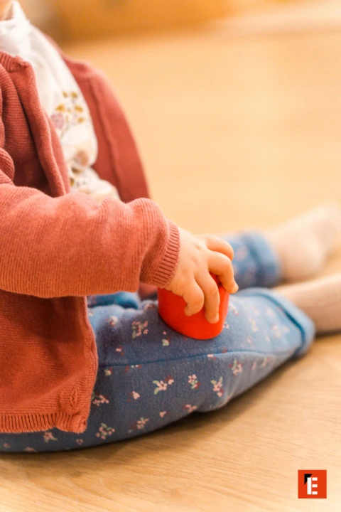 main denfant tenant un jouet rouge