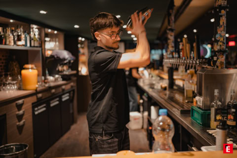 barman secoue un shaker dans un bar chaleureux