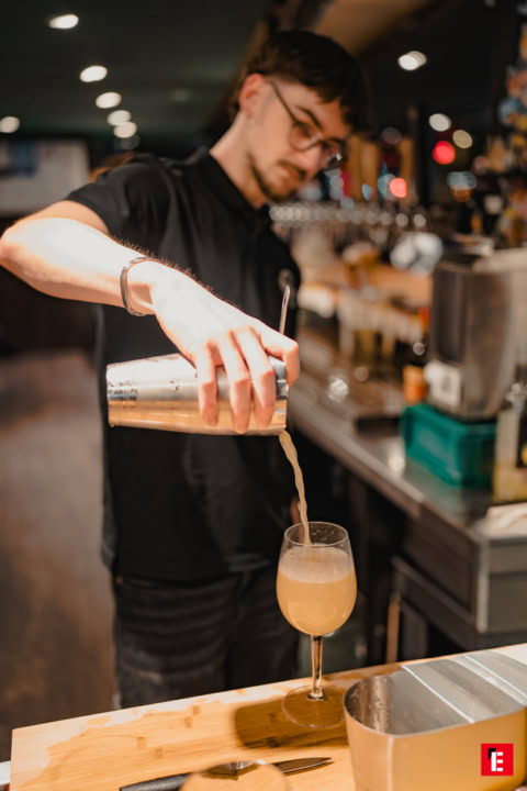 barman versant un cocktail mousseux au shaker