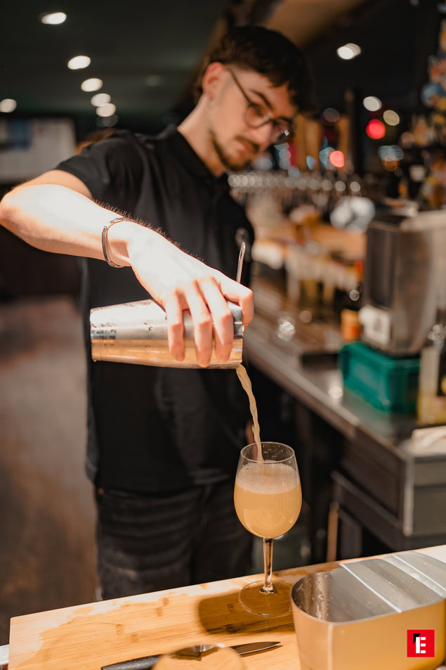 barman versant un cocktail mousseux au shaker