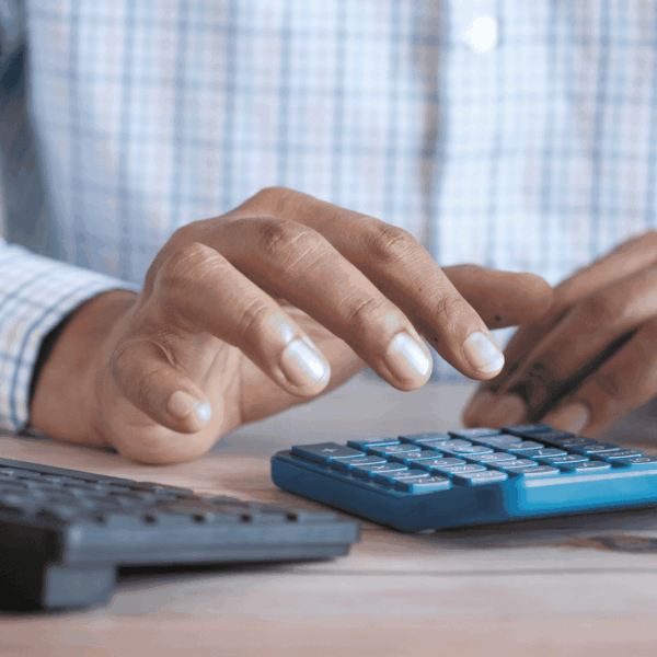close up of a man's hands next to a calculator and a keyboard. the man's wearing a shirt