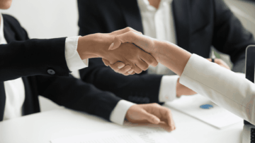 close up of the arms of two people shaking hands