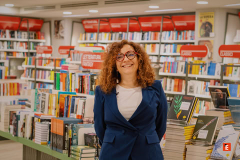 donna sorridente in libreria nella sezione fantasy