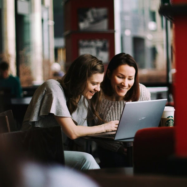 due donne in un bar sul loro computer che ridono