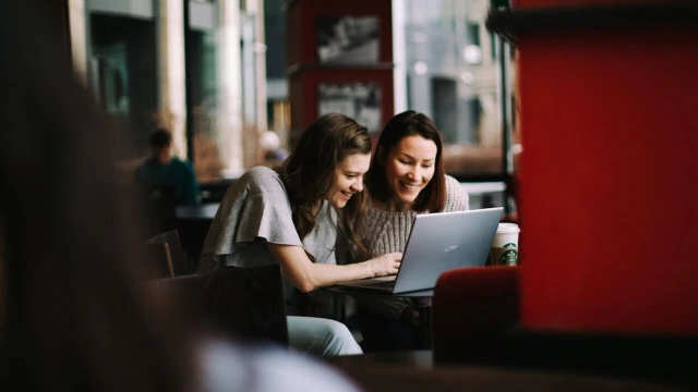 due donne in un bar sul loro computer che ridono