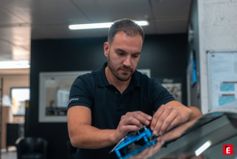 mécanicien en atelier applique un produit sous le capot