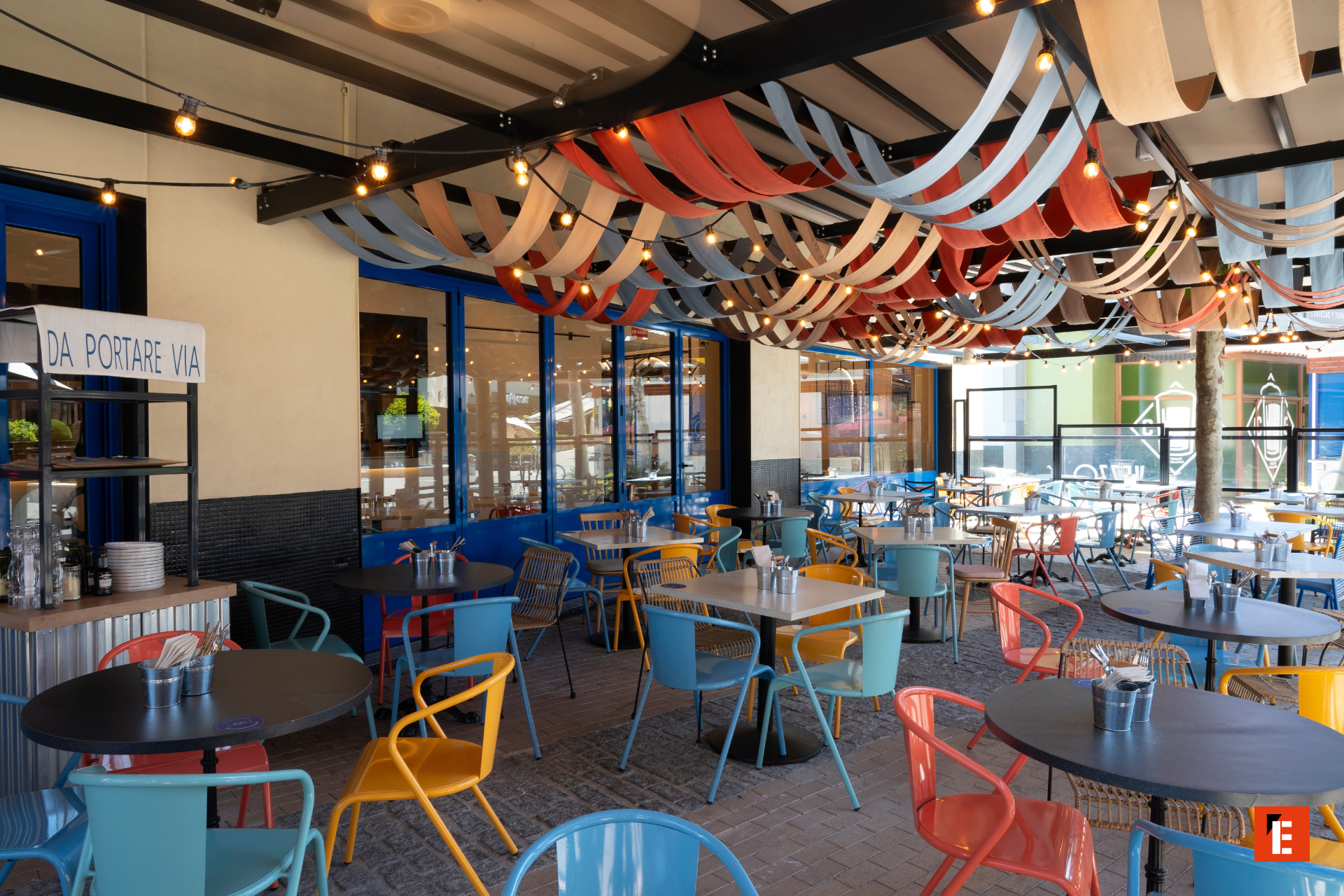 terraza de cafetería cubierta con luces y sillas coloridas