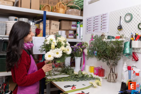 Hombre sonriente sosteniendo flores en taller.