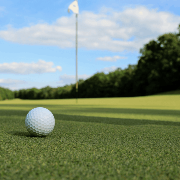 golf course with a white flag in the background and a golf ball in the foreground