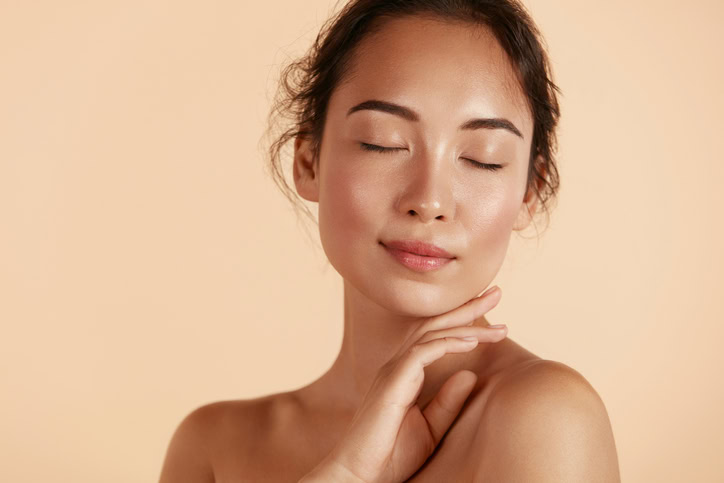 femme souriante appliquant une crème soin visage