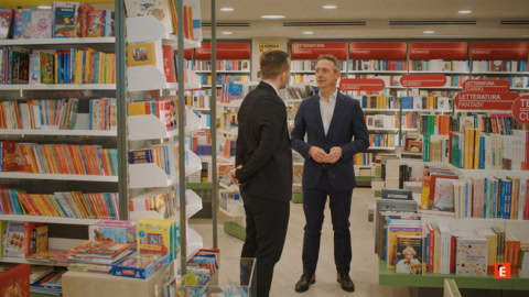 libreria: scaffali per bambini e dialogo tra due uomini