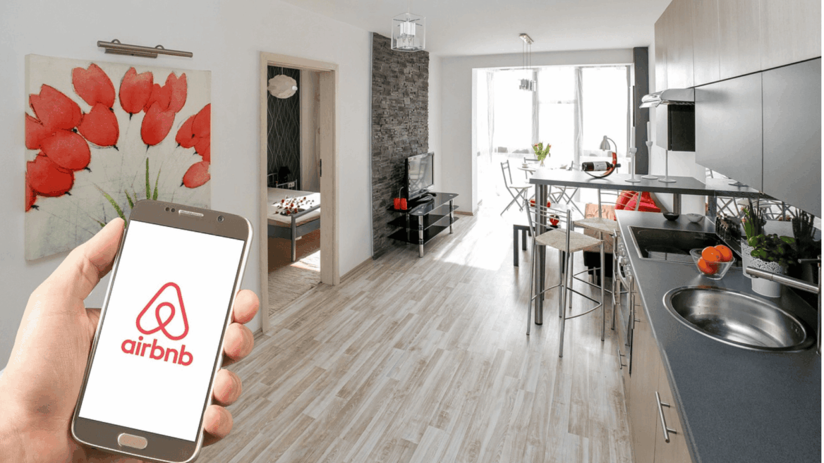 mano con móvil y app airbnb en apartamento