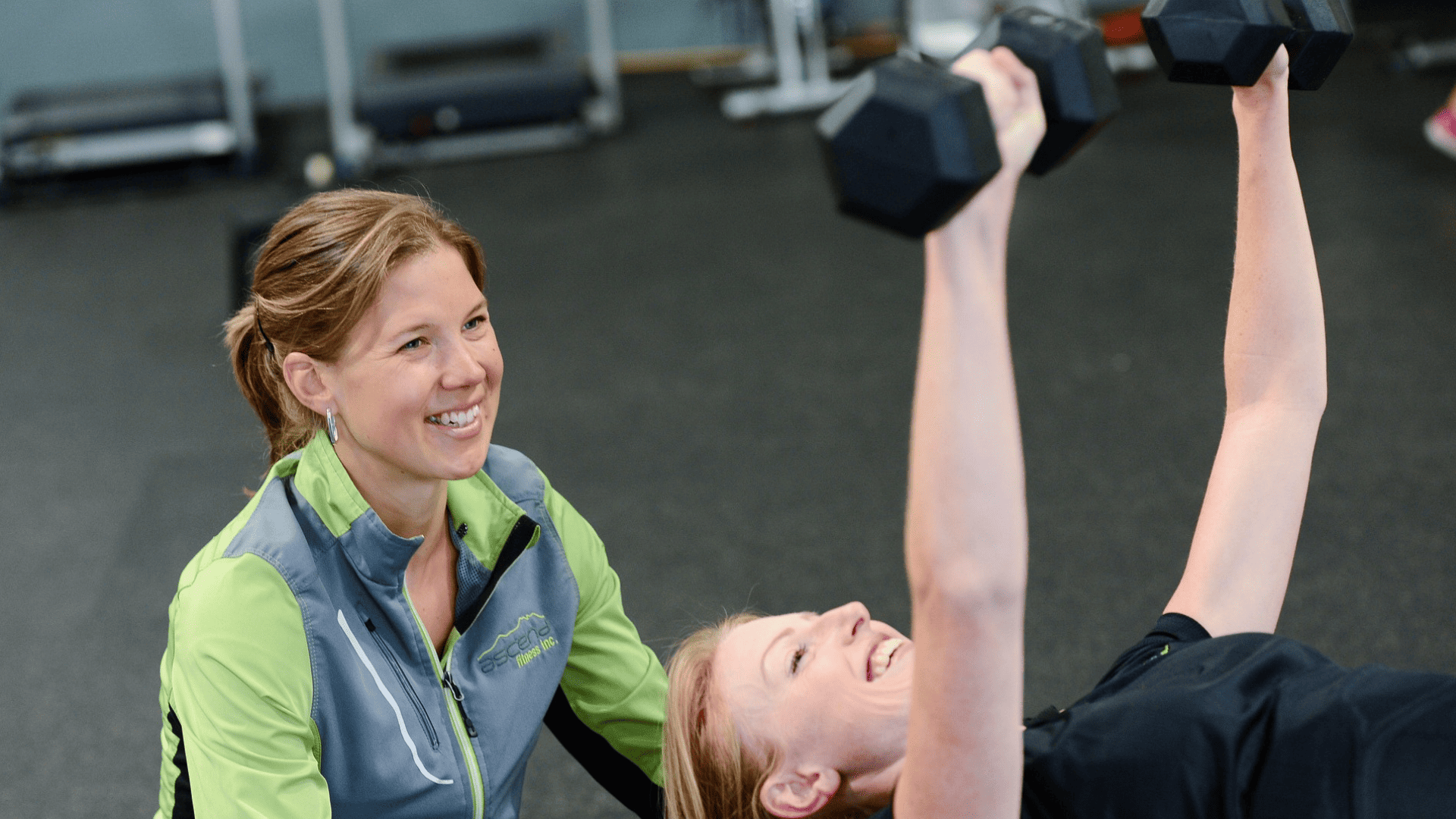 mujer haciendo pesas con entrenadora