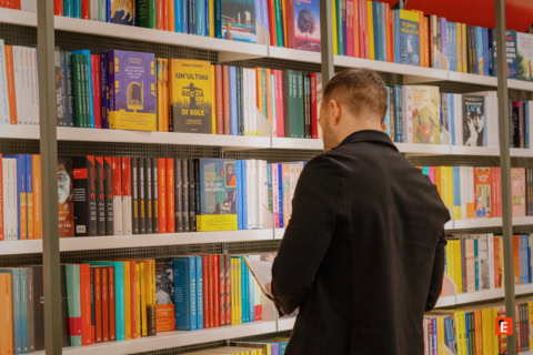 lettore in libreria tra scaffali colorati