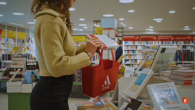 persona che sfoglia libri con borsa rossa