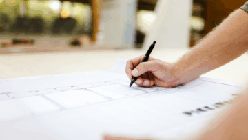 White hand writing something on a sheet of paper