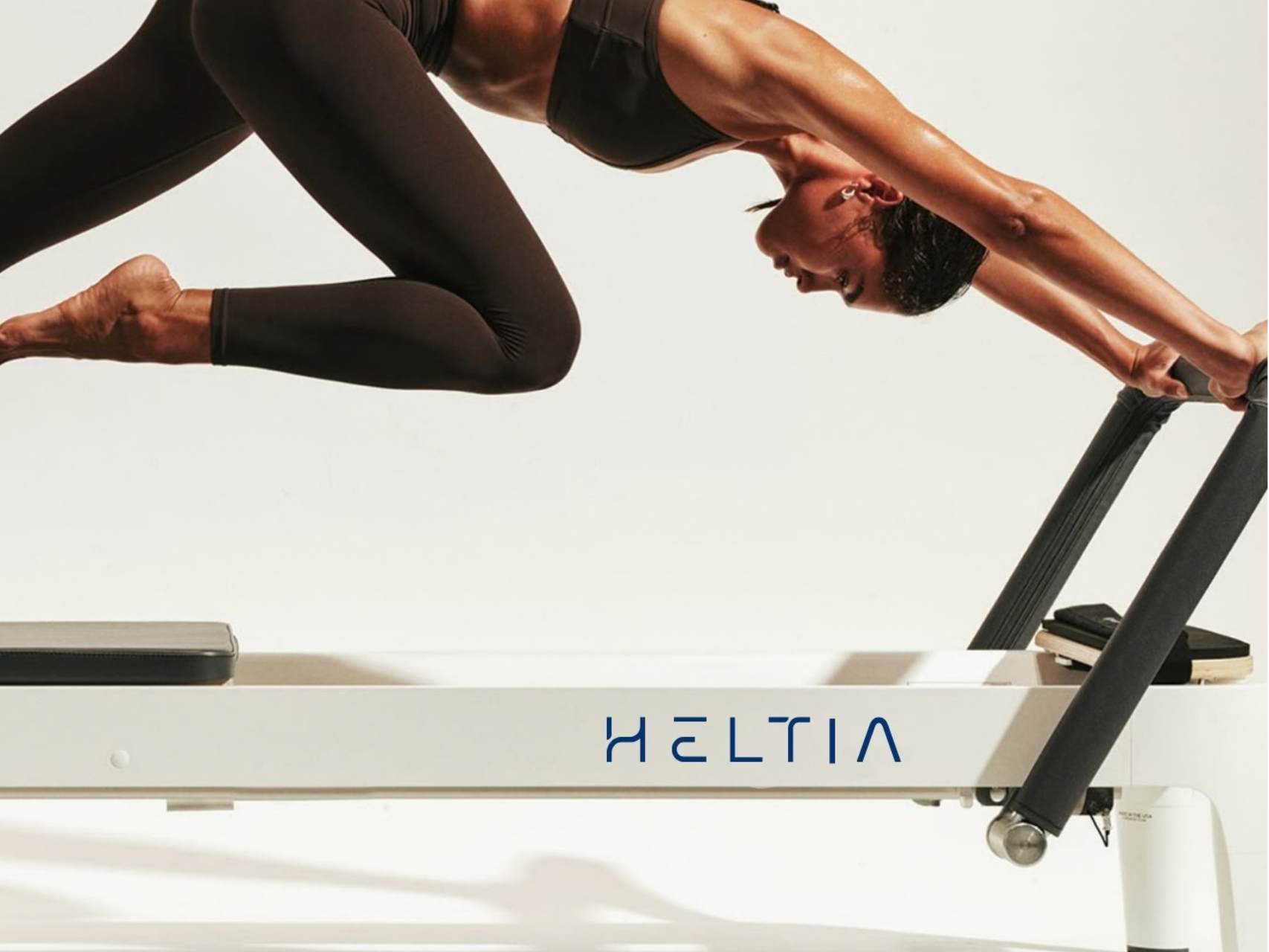 mujer en reformer pilates, pose atlética elegante
