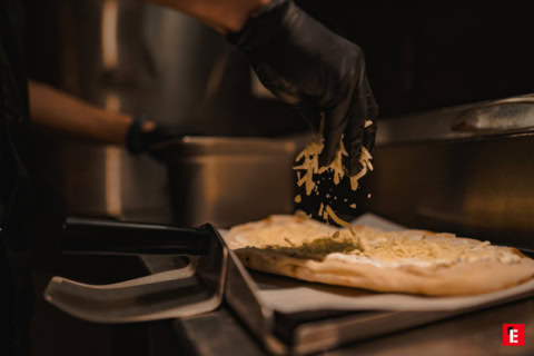 pizza au fromage et pesto, main gantée