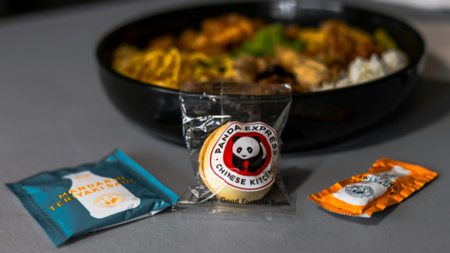 plate of panda express food with vegetables meat and rice, and a fortune cookie as well as sauces