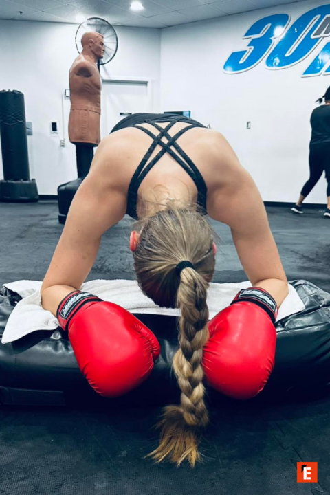 female boxer with red gloves resting in gym