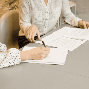 two women with shirts signing a document together, we do not see theur faces
