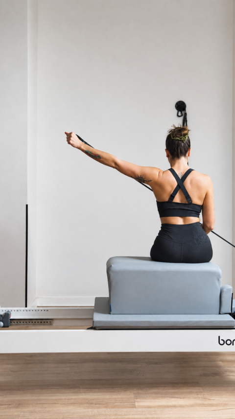 mujer haciendo pilates reformer en estudio minimalista