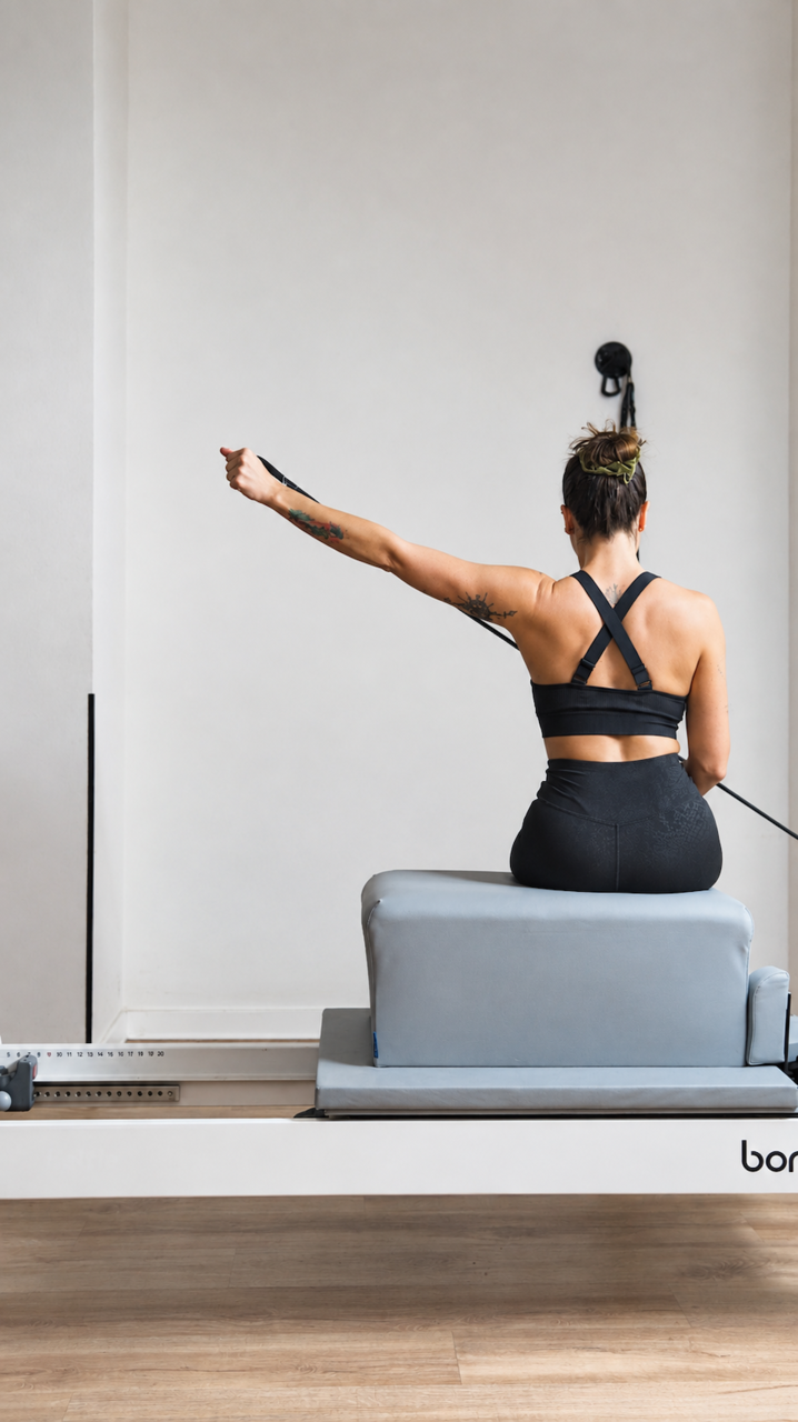 mujer haciendo pilates reformer en estudio minimalista