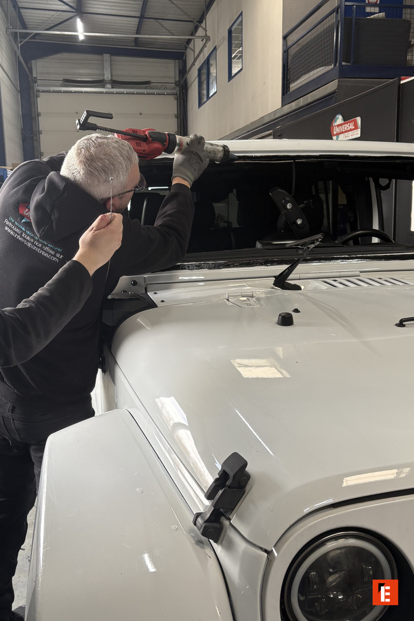 technicien remplace le pare brise dun 4x4 en atelier