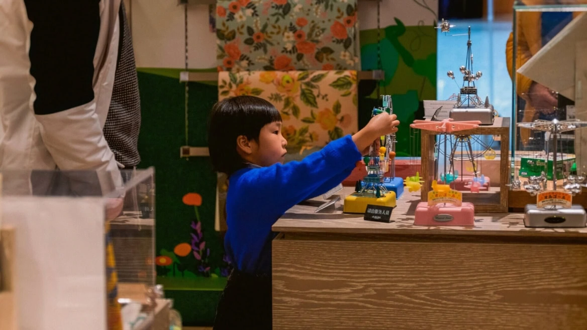 bambino in maglione blu esplora giocattoli meccanici