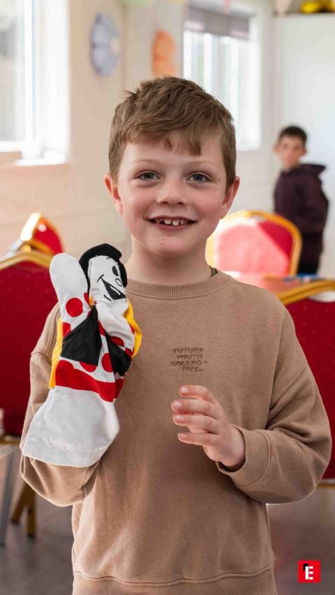 smiling boy with hand puppet in classroom
