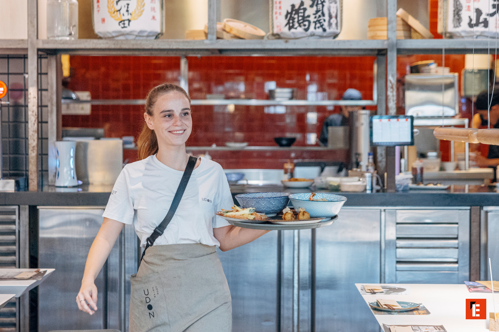 camarera sirviendo udon y tempura en cocina abierta