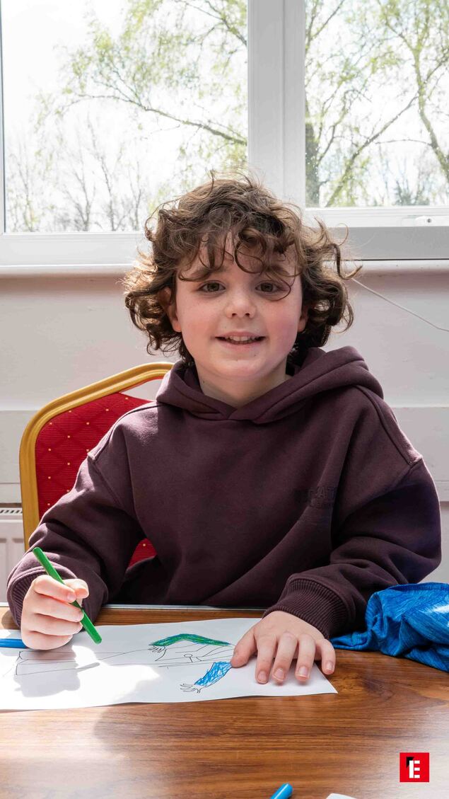 smiling curly haired child drawing at sunlit table