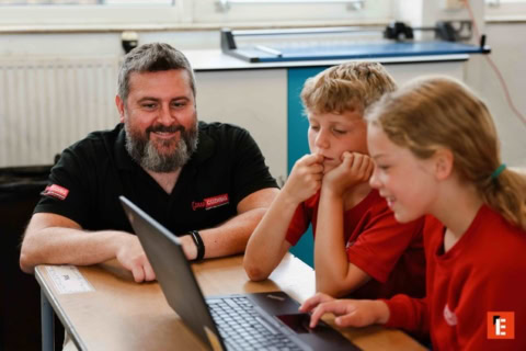 teacher and pupils collaborating on a laptop